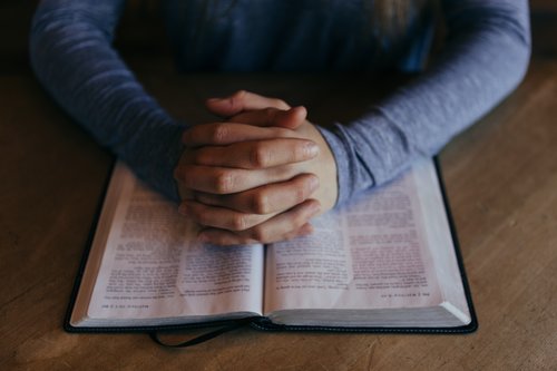 raamattu ja kädet rukouksessa