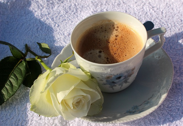 kuvassa kahvikuppi ja valkoinen ruusu